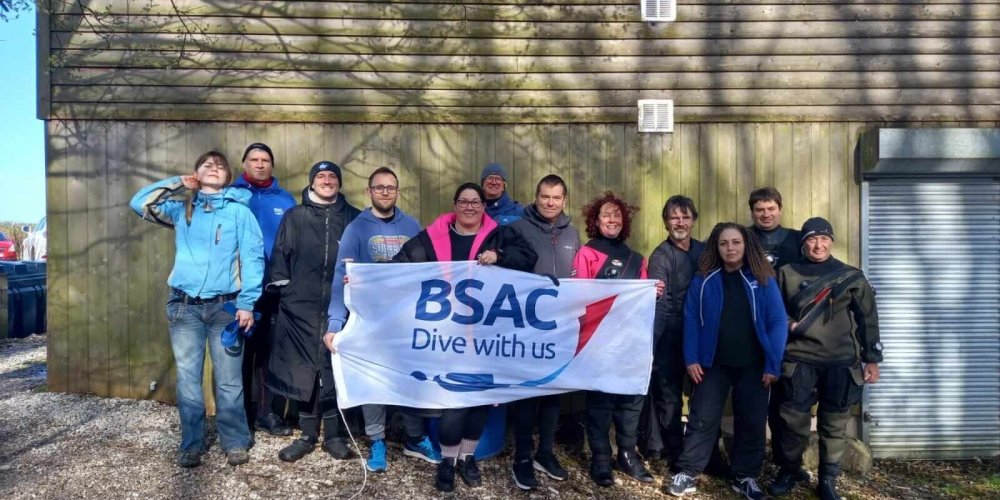 A picture of all participants of the Buoyancy and Trim workshop hosted by Wigan Scuba Divers in collaboration with several other BSAC branches, proudly holding the BSAC banner.